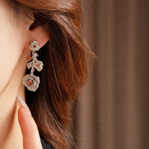 Macro shot of silver rose earrings with red stones on a model in vintage palace style