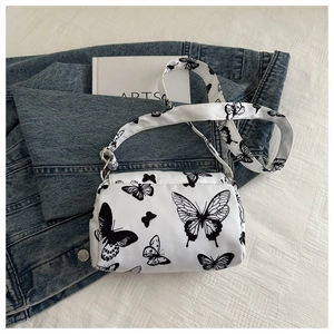 Close-up of white crossbody bag with black butterfly prints on fabric and wide strap