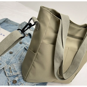 Detail of sage green nylon messenger bag featuring durable woven strap and side pocket