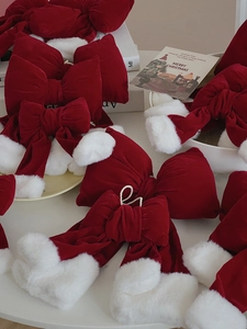 Close-up of red velvet Christmas bow with white faux fur trim and holiday decor