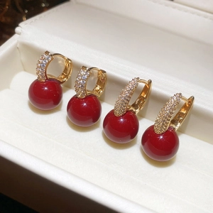 Close-up of red resin bead earrings with gold-plated zircon pavé hoops in a jewelry box
