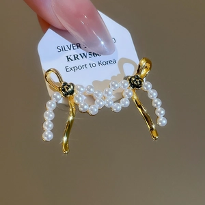 Detail of 18k gold plated pearl bow earrings with small black rose accent on white card