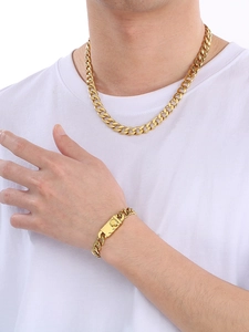 Close-up of gold cuban link chain necklace and bracelet set on a white t-shirt