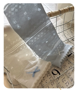 Detailed macro view of lace knit socks featuring heart patterns and delicate blue bows