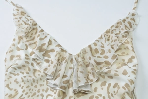 Détail en gros plan du décolleté en V profond avec bords à volants sur une robe léopard