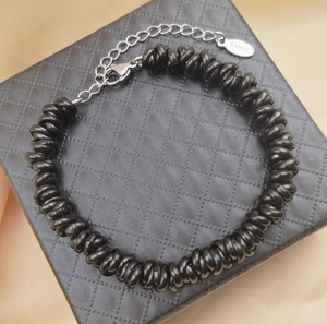 Detail of beaded bracelet with stainless steel lobster clasp and engraved brand tag