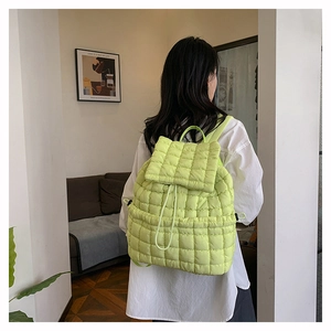 Dettaglio dello zaino trapuntato verde con coulisse e patta indossato dalla modella