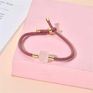 Détail du bracelet en corde tressée rose avec fermoir doré et perle cube claire