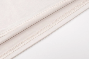 Detailed close-up of beige knitted fabric texture and precise double-needle hem stitching