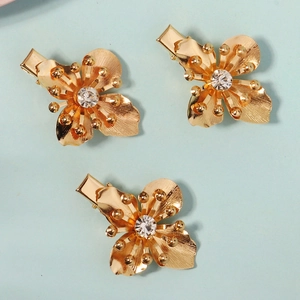 Detailed view of three gold metal flower hair clips with sparkling crystal centers