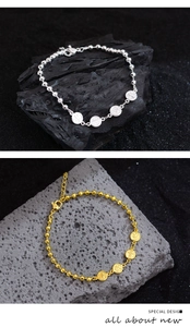 Detail of beaded metal bracelets in gold and silver finish with embossed round charms