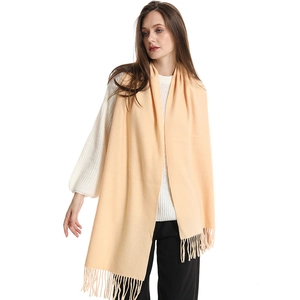 Close-up of soft beige cashmere-like scarf featuring delicate tassel fringe details