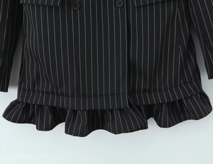 Gros plan d'un blazer noir à rayures avec ourlet à volants et détails de boutons