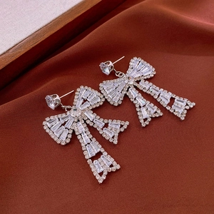 Détail de boucles d'oreilles nœud argentées avec cristaux sur fond de velours marron