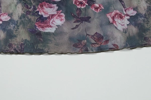 Close-up of pink rose print on gray-purple mesh fabric with ruffled edges detail