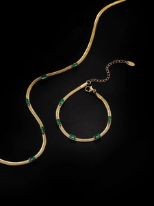Dettaglio del set collana e bracciale a catena serpente dorata con zirconi verdi
