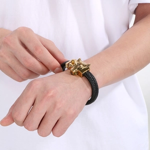 Close-up of a braided leather bracelet with a gold-tone wolf head and punk skull details