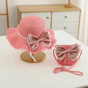 Dettaglio cappello di paglia rosa e borsa con fiocchi in pizzo floreale per bambine