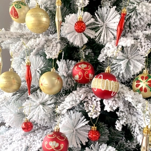 Palline di Natale rosse e oro e renne appese a un albero innevato