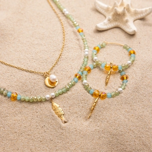 Bohemian glass bead necklace and earrings set with fish pendant on beach sand