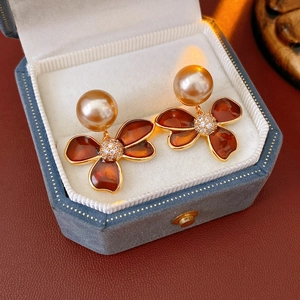 Vue détaillée de boucles d'oreilles fleurs en ambre avec perles dorées en écrin bleu