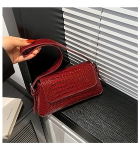 Detailed view of a red crocodile pattern leather handbag with silver hardware and strap