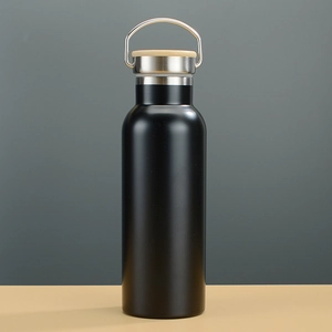 Detail of matte black insulated bottle with natural bamboo lid and steel handle