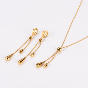 Close-up of golden water drop tassel earrings and adjustable lariat necklace on white
