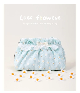 Detail of light blue lace makeup bag featuring daisy embroidery and a white ribbon bow