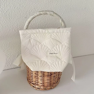 Detailed close-up of quilted fabric texture and woven rattan base on shell makeup bag