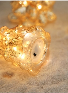 Close-up of glass Christmas tree lamp base with black toggle switch and battery compartment