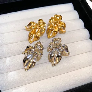 Floral stud earrings in gold and silver finish displayed in a white velvet jewelry box