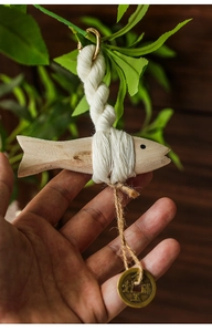 Detail of hand-carved wooden fish pendant with cotton rope and ancient copper coin