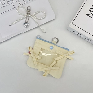 Dettaglio del porta carte crema con fiocco, finestra in PVC e portachiavi con perle