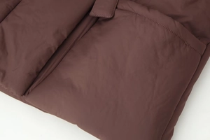 Detailed macro shot of the premium brown padded jacket fabric and neat quilted stitching