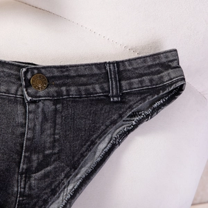 Dettaglio di pantaloncini di jeans a vita alta con orlo sfrangiato e bottone inciso