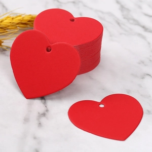 Red heart-shaped kraft paper gift tags with pre-punched holes on white marble background