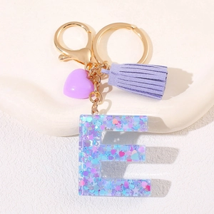 Macro view of a resin letter E keychain with purple tassels and glitter star accents