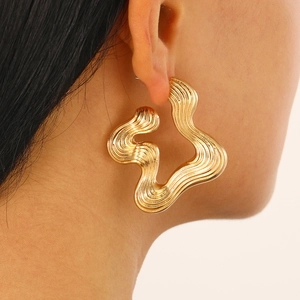 Close-up of elegant gold abstract wavy hoop earrings worn on model for stylish look