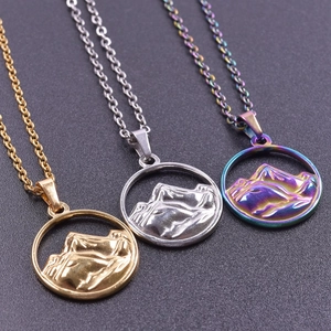 Macro shot of 18K gold, silver, and iridescent mountain pendants on a black background