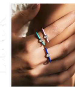 Detailed view of colorful enamel heart rings with sparkling zircon stones on a hand