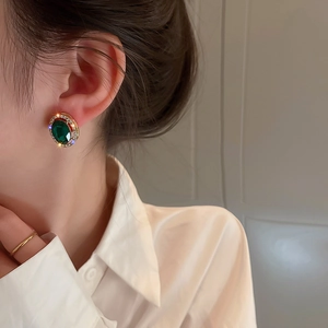 Dettaglio macro di orecchini vintage in cristallo smeraldo con strass su modella