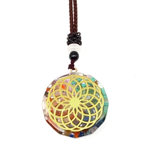 Detail of Orgone energy pendant with colorful natural stones and golden Flower of Life