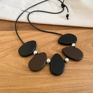 Close-up of minimalist resin stone pendant necklace with adjustable black cord detail