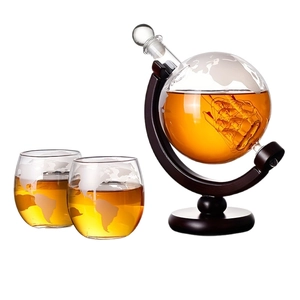 Globe whiskey decanter with sailing ship inside and two etched glasses on wood stand