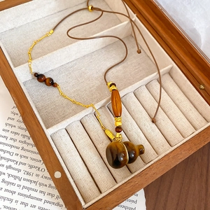 Macro view of tiger eye stone gourd pendant with wooden beads on a woven rope chain