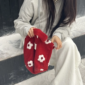 Detail of red plush handbag featuring white flower patterns and soft fleece texture