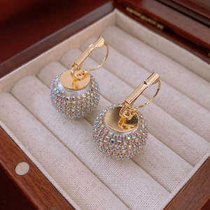 Macro shot of gold hook earrings featuring spheres paved with colorful AB rhinestones