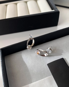 Detailed view of silver twist earrings with round zircon inlay on a jewelry box