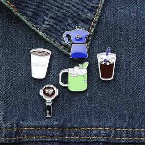 Detail of five coffee and tea enamel pins on denim jacket showing mocha pot and cups
